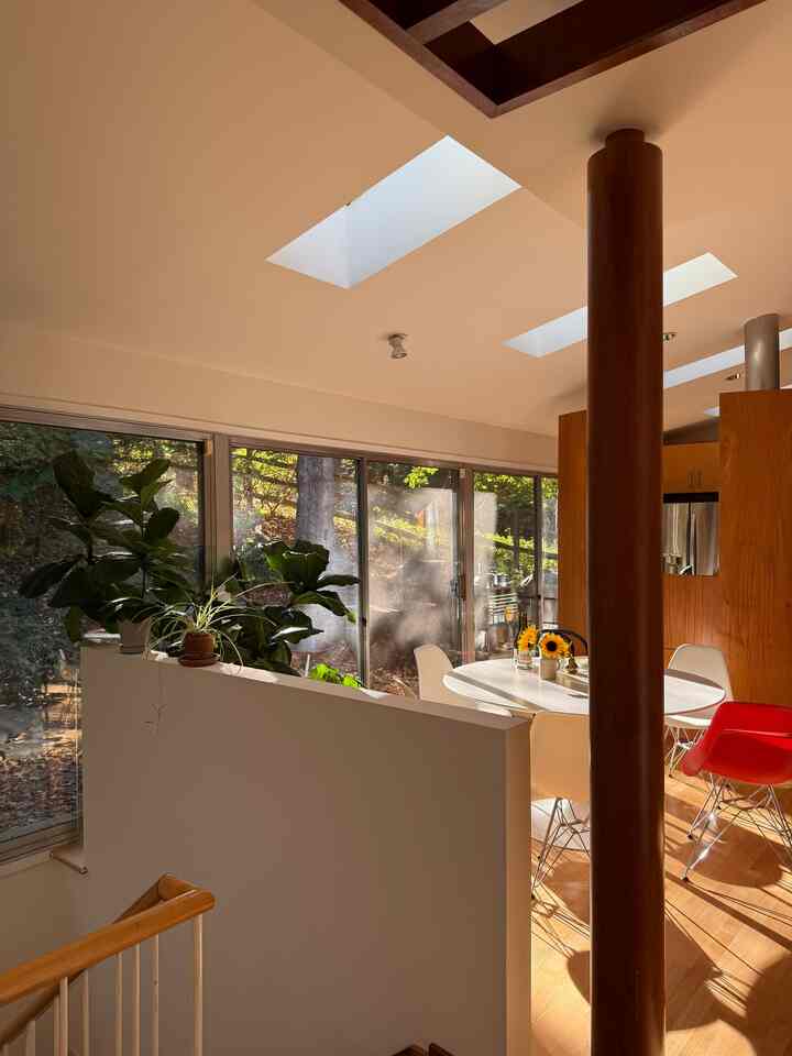 Warm wood tone and white dining room with large windows and plants, filled with natural light creating a cozy fall atmosphere
