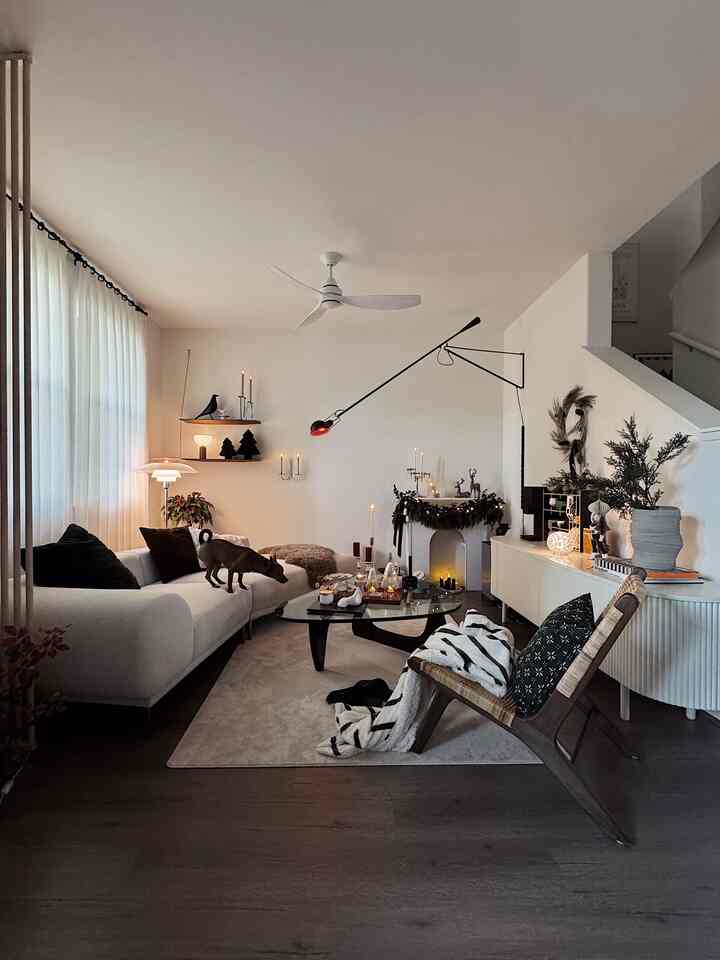 Natural living room in white and brown tones featuring Christmas garland, lit candles, pet, and cozy blankets