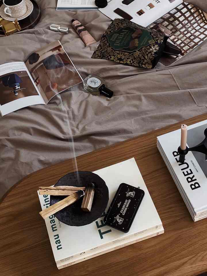 Natural color bedroom featuring beige bedspread and wood tone coffee table with candle and books arranged, cozy atmosphere