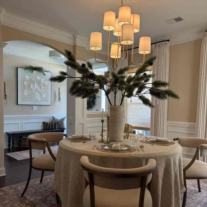 Warm beige-toned dining room featuring a round table with chairs, set for formal occasion with elegant decor