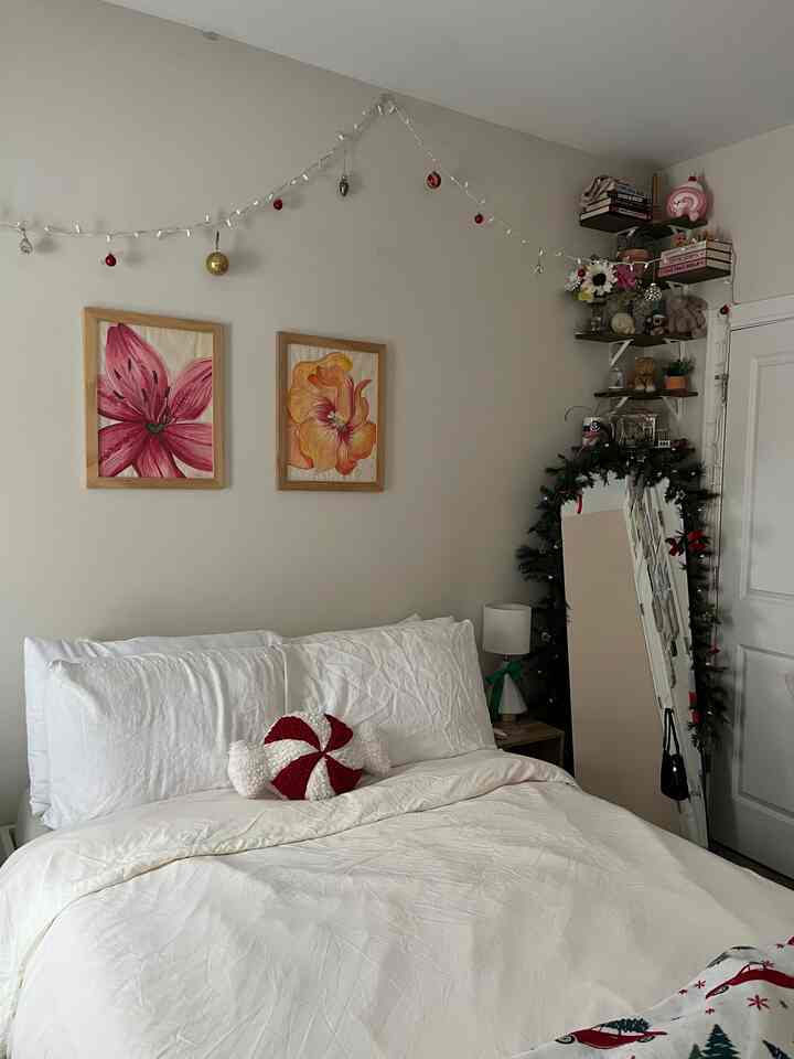 White and neutral-toned bedroom featuring Christmas garland and peppermint pillow creating a cozy ambiance