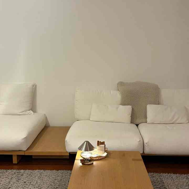 A white and wood tone living room featuring minimal furniture and candle lighting creating a cozy atmosphere