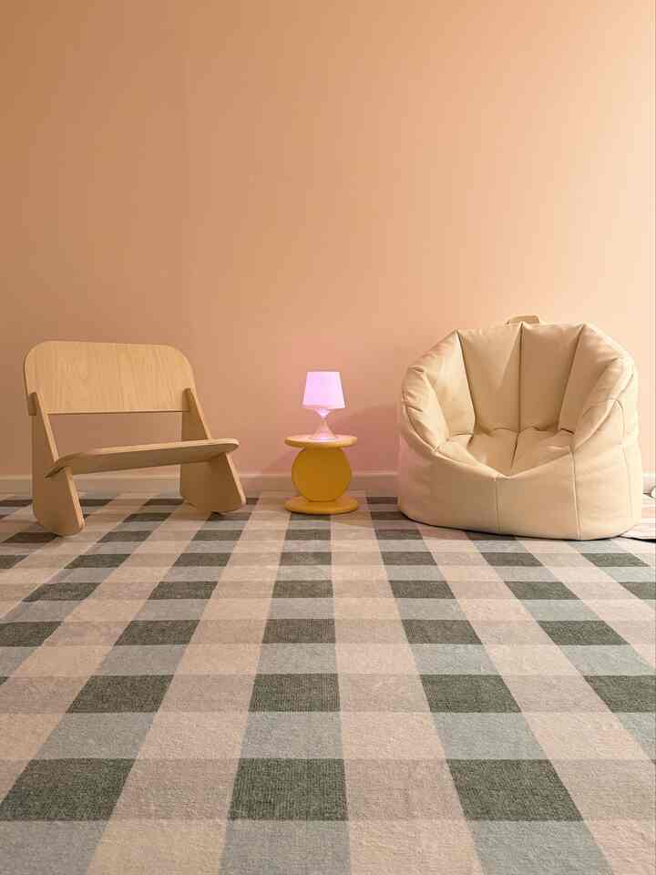 Beige-toned kids' room featuring a natural wood child chair, beige bean bag, yellow stool, and table lamp creating a cozy atmosphere