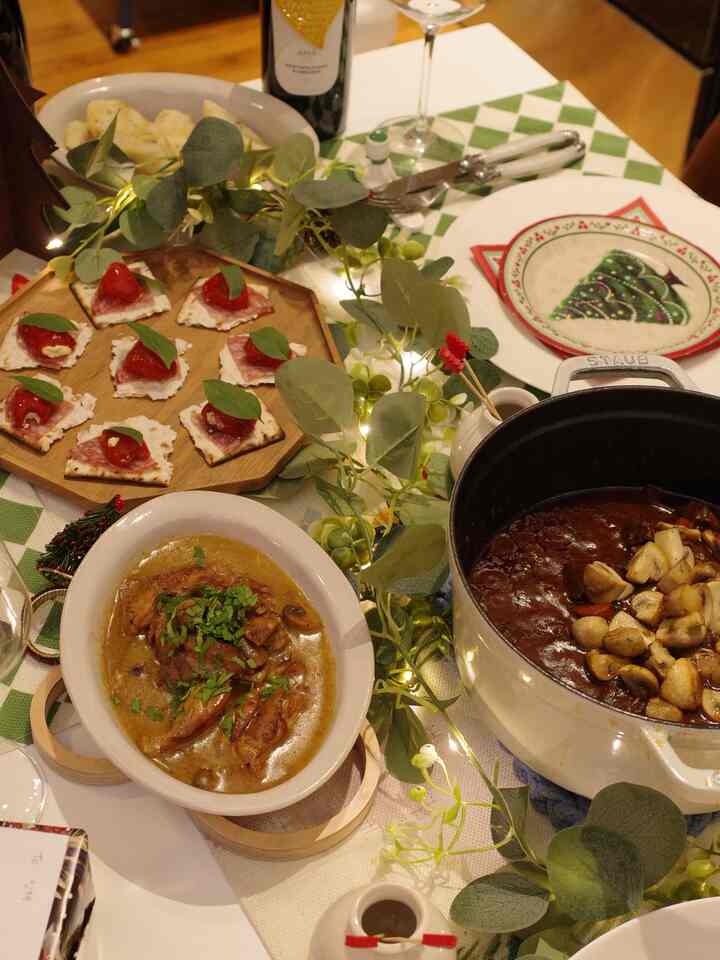 A green and wood-toned table set with Christmas decorations and serving dishes for a home party atmosphere
