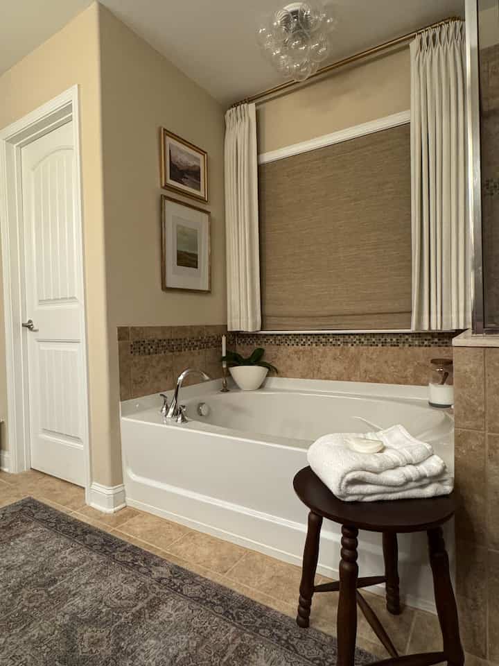 Beige and brown toned bathroom featuring wooden stool with white towels, creating a cozy atmosphere