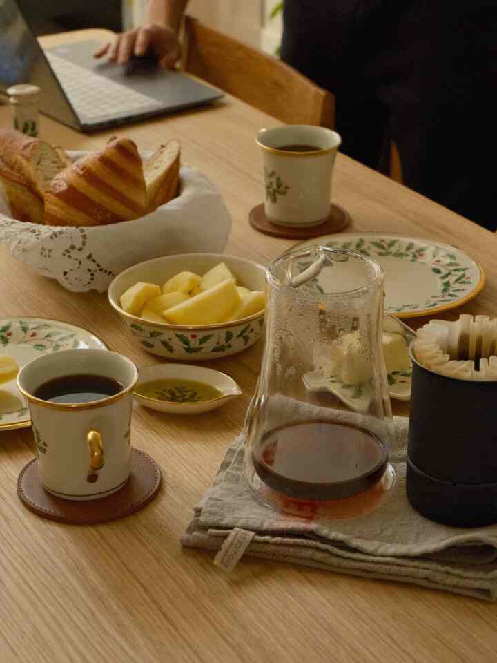 Warm brown dining table featuring coffee, bread, and fruit creating a cozy home cafe atmosphere