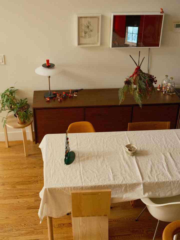 Natural wood tones and white tones blend in a dining room featuring Christmas decor and a table lamp with a cozy atmosphere