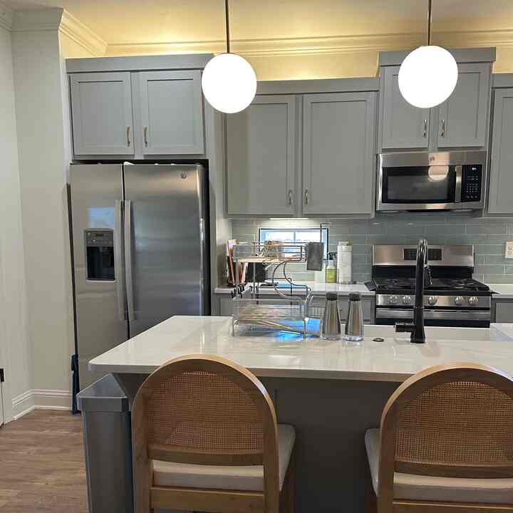 Gray-toned clean kitchen with a central island and dining chairs, showcasing a modern space