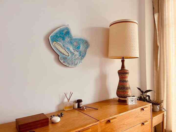Natural-toned bedroom nightstand featuring a lamp, clock, candles, and diffuser creating a cozy atmosphere