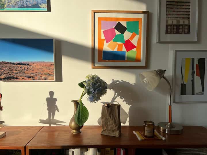 Warm brown wooden furniture with a gold vase and colorful art frames decorating a living room wall space