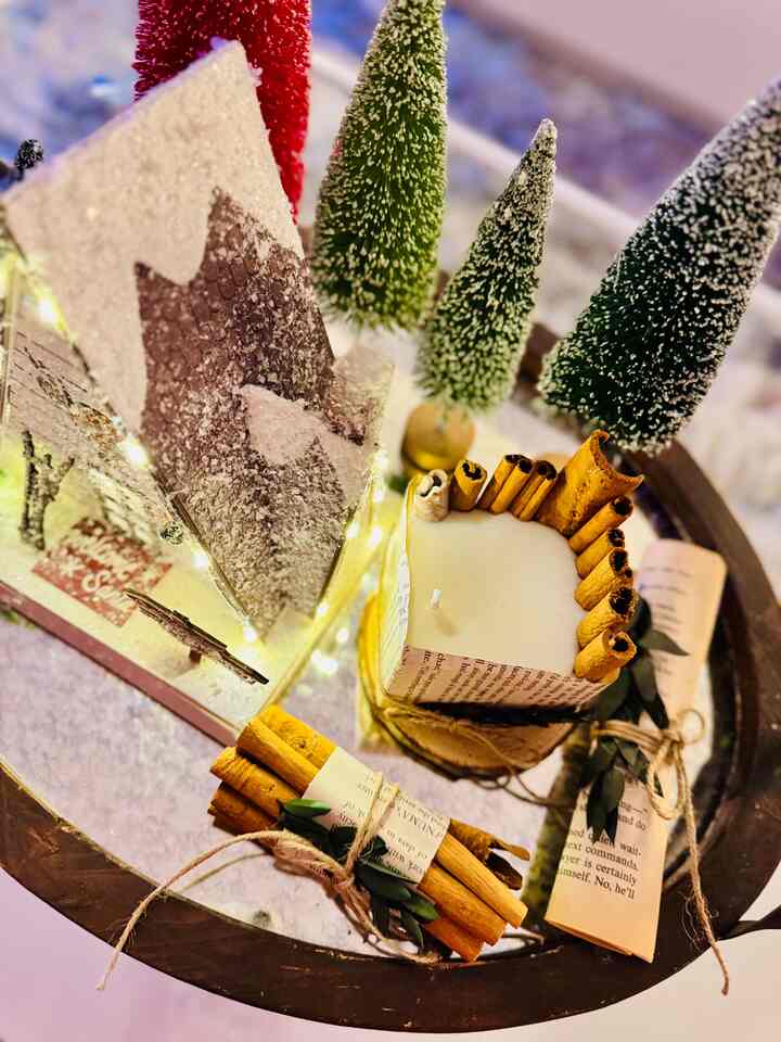 Warm brown toned living room coffee table featuring a scented cinnamon candle and miniature Christmas trees with cozy decor