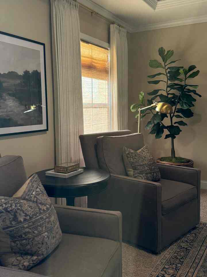 Beige-walled living room featuring armchairs, side table, and floor lamp with cozy atmosphere
