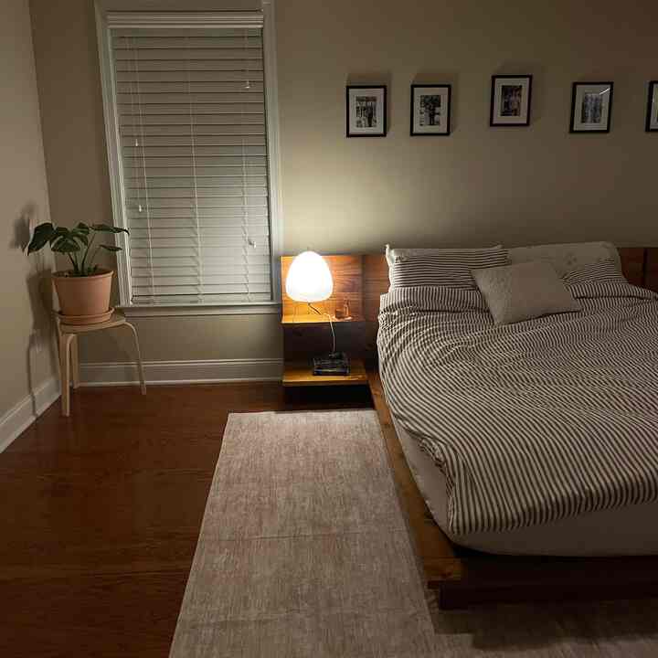 Cozy bedroom with warm wood tones and beige colors featuring wooden bed frame and table lamp on nightstand