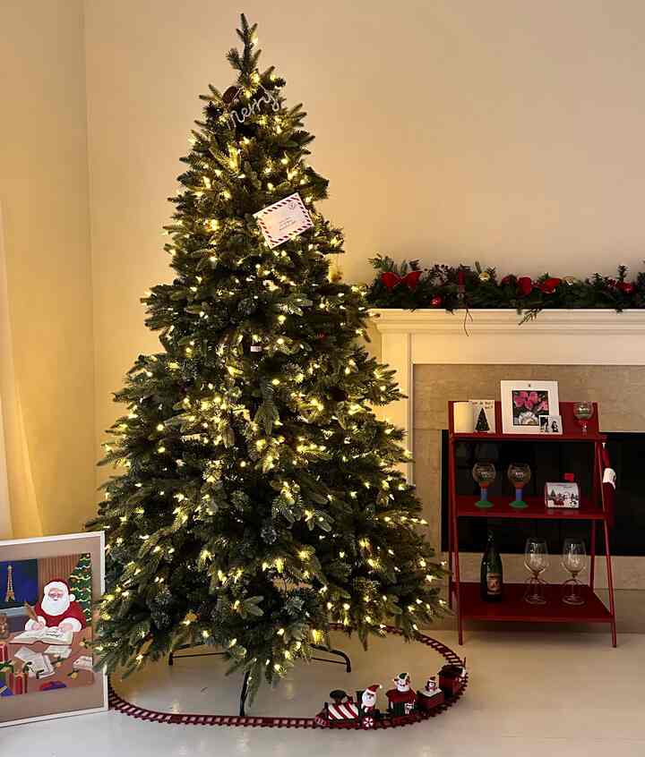 Warm yellow-green toned living room featuring a decorated Christmas tree and festive shelf with cozy atmosphere