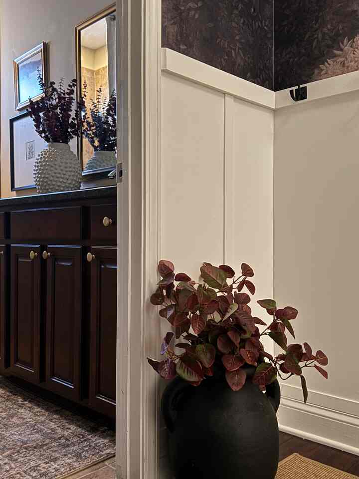 Bathroom entrance space featuring dark brown wood cabinetry and black vase with red leaves