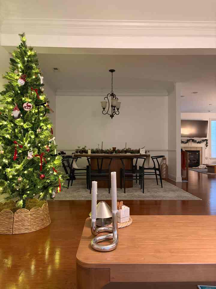 White and brown toned dining room featuring a decorated Christmas tree and candle accents creating a cozy winter decor