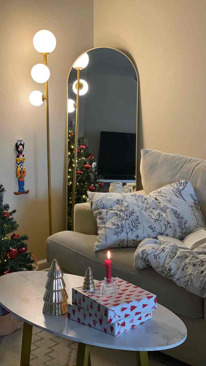 White and gold toned living room featuring beige sofa, marble coffee table, and a decorated Christmas tree creating a cozy atmosphere