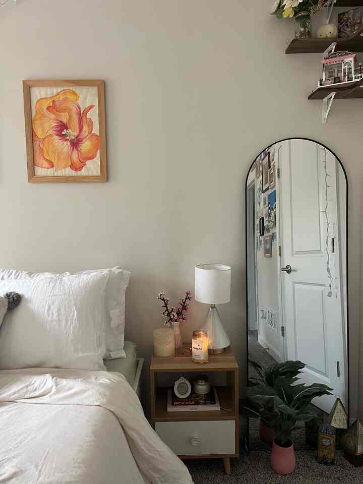 White and wood tone bedroom featuring a nightstand and floor mirror with a minimal and natural atmosphere
