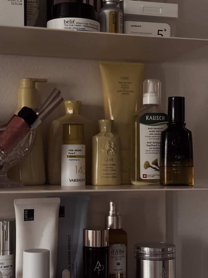 White-toned wall shelf filled with various skincare and haircare products in a bathroom space