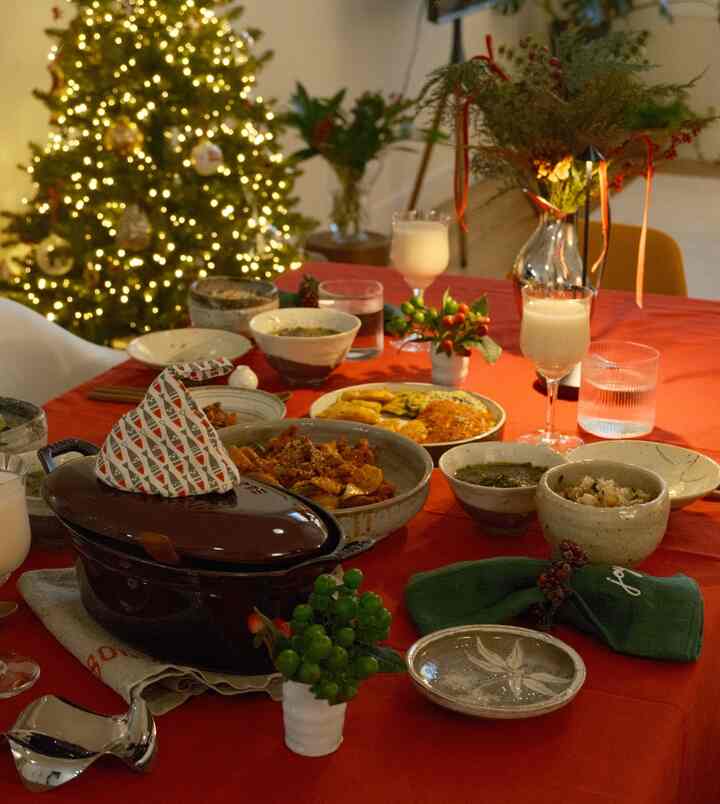 Red-toned dining room featuring a Christmas tree and Korean comfort food laid out on a festive home party table