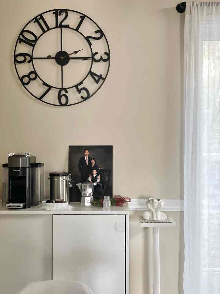 Bright white-toned home cafe space featuring a large black wall clock and a Nespresso coffee machine with a clean interior