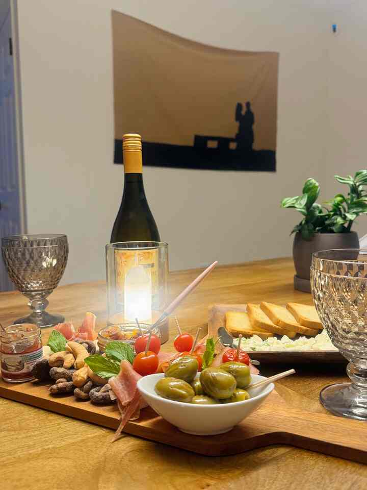Warm natural-toned dining space featuring wine glasses and a table lamp creating a home bar atmosphere
