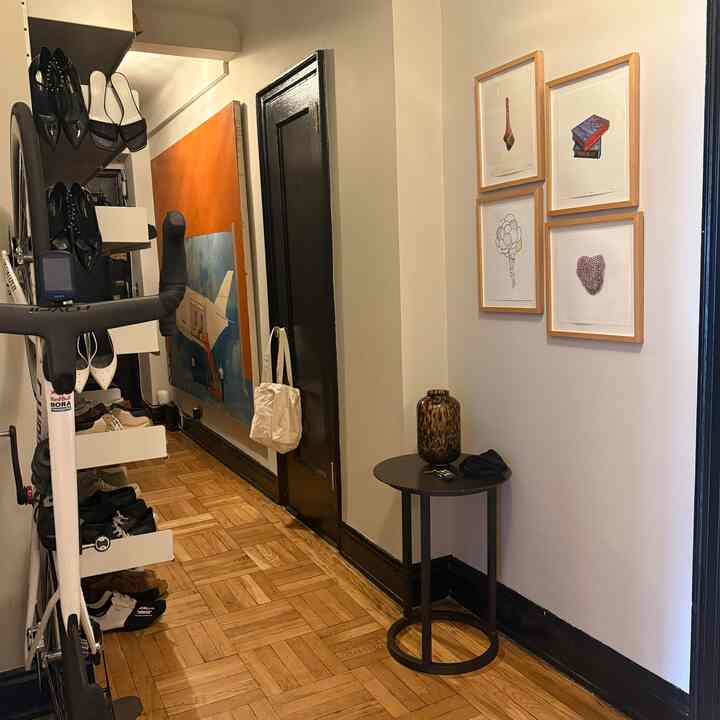 Wood tone floor narrow entrance with side table and framed art on walls, cozy and functional space