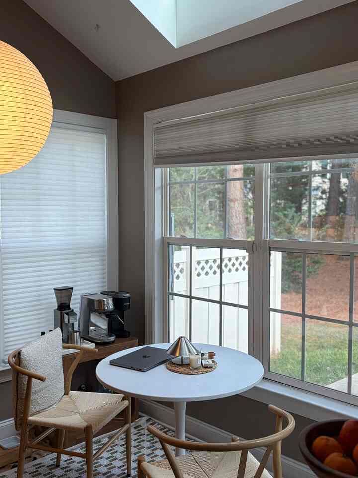 Beige and white toned dining room featuring a round table and natural wood chairs creating a cozy atmosphere
