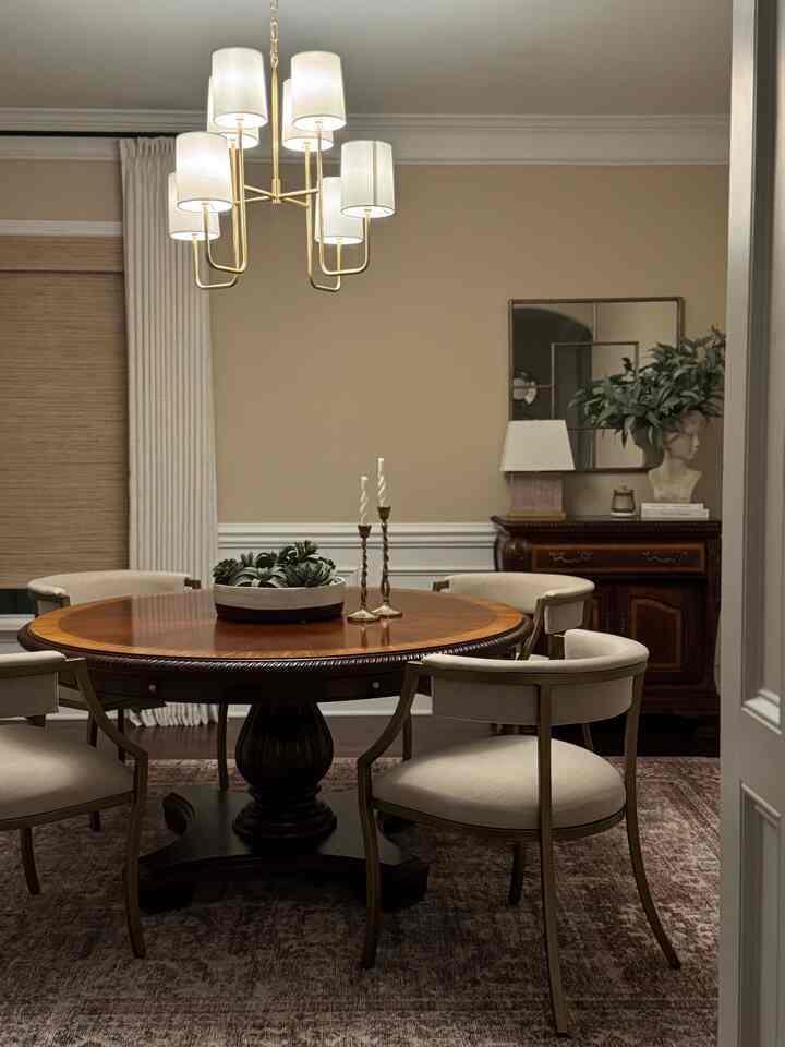 Classic dining room with beige and wood tones, featuring a round dining table and chairs, chandelier, and plant for an elegant atmosphere