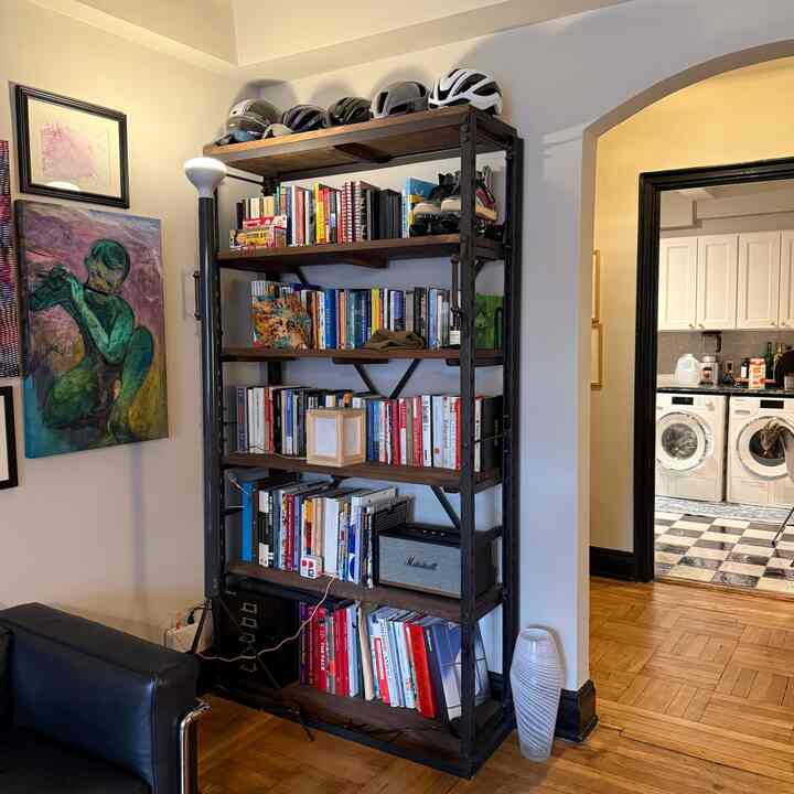 Brown wood tone and black metal living room featuring bookshelf and floor lamp with a clean, organized atmosphere
