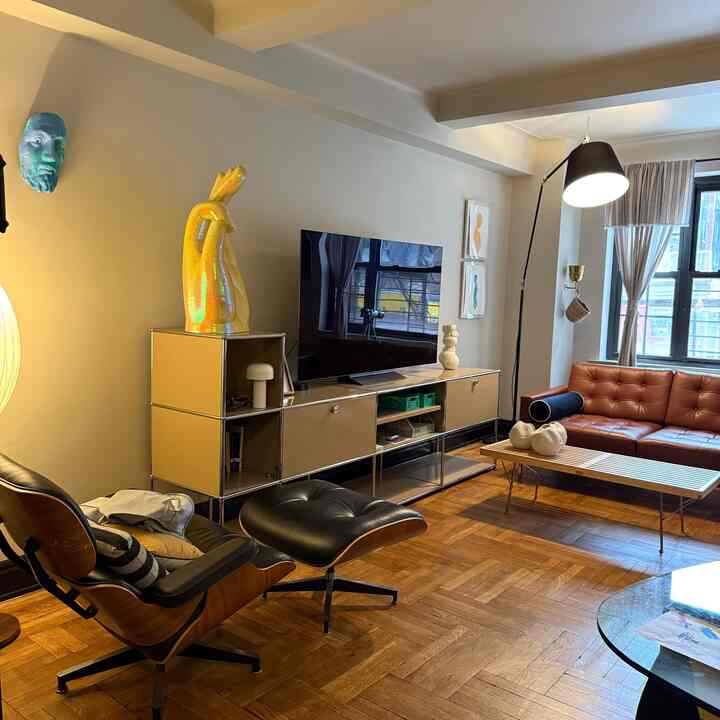 Warm brown wood-tone modern living room featuring leather sofa, armchair, TV stand, and floor lamp in cozy setting
