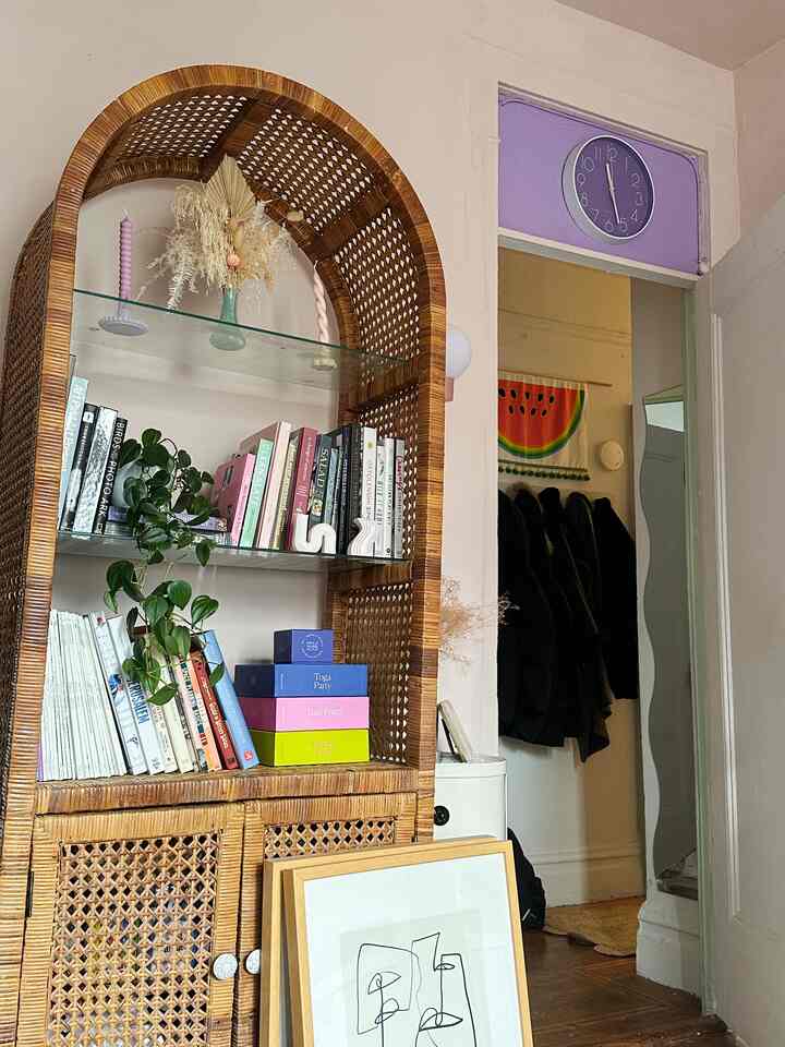Natural wood tone bohemian living room featuring rattan shelf and purple clock with cozy, layered atmosphere