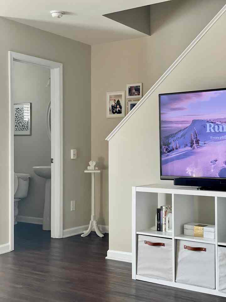 Simple living room in white and brown tones featuring TV stand and storage bins with clean atmosphere.