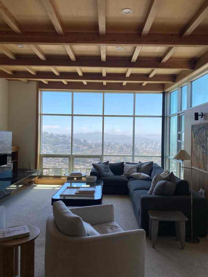 Natural wood tone and gray living room featuring a large window and sectional sofa with a modern cozy atmosphere