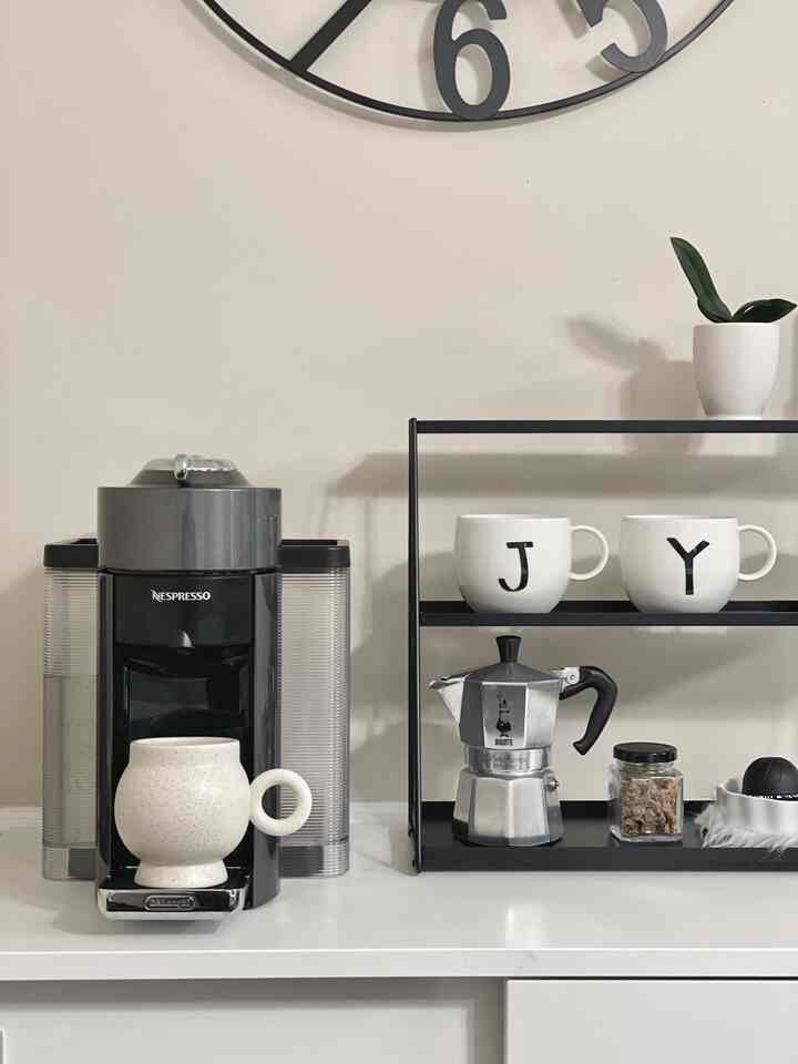 White and black toned kitchen space featuring a coffee machine and mugs in a tidy home cafe setup