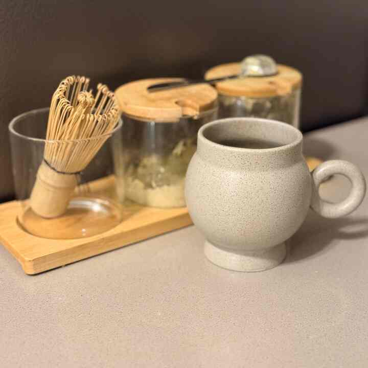 Natural color tone kitchen space featuring wooden tray, teacup, and matcha whisk set creating a cozy home cafe atmosphere