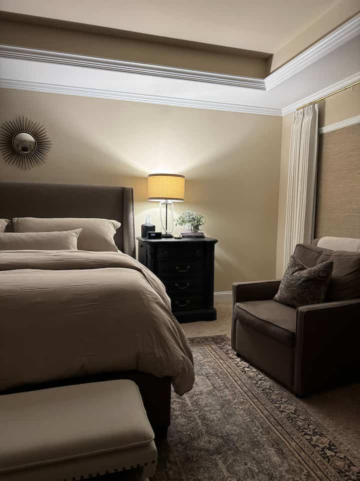 Beige-toned bedroom featuring a bed, armchair, and nightstand with a cozy and natural atmosphere