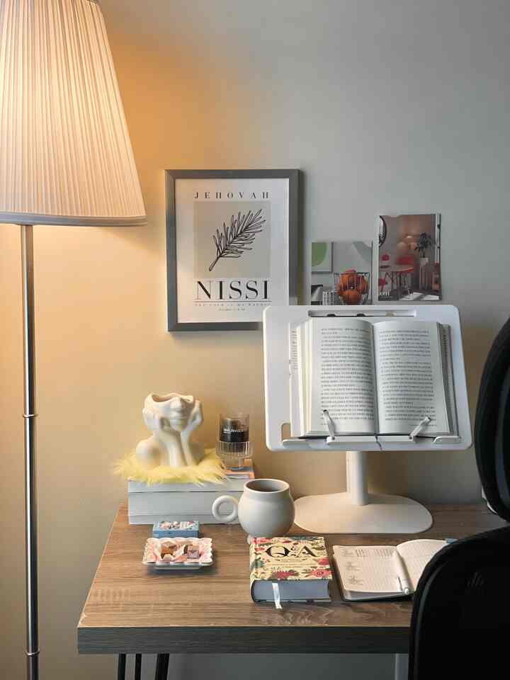 Soft beige and white toned home office space featuring desk, mug, books, and floor lamp with cozy ambiance