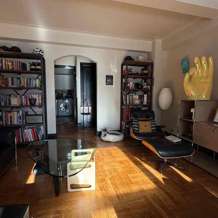 A warm wood-tone floor and white walls living room featuring an Eames lounge chair and Noguchi coffee table with a cozy atmosphere