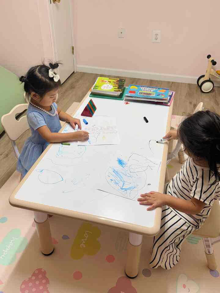 Pastel-toned kids' room featuring a kids' desk and chairs with children drawing, creating a cozy atmosphere