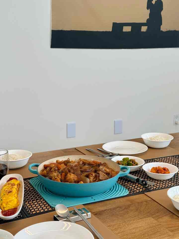 A clean dining space with a brown wooden table featuring white plates, various bowls, and a turquoise pot