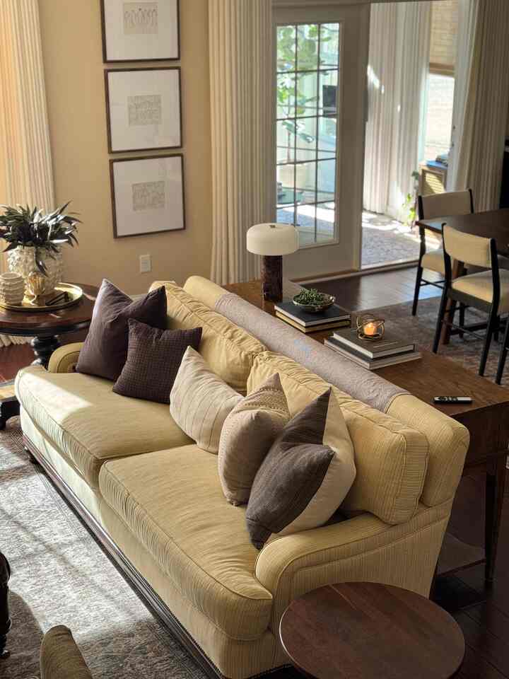 Warm beige and wood tone living room featuring a cream sofa with cushions and side tables, creating a cozy atmosphere