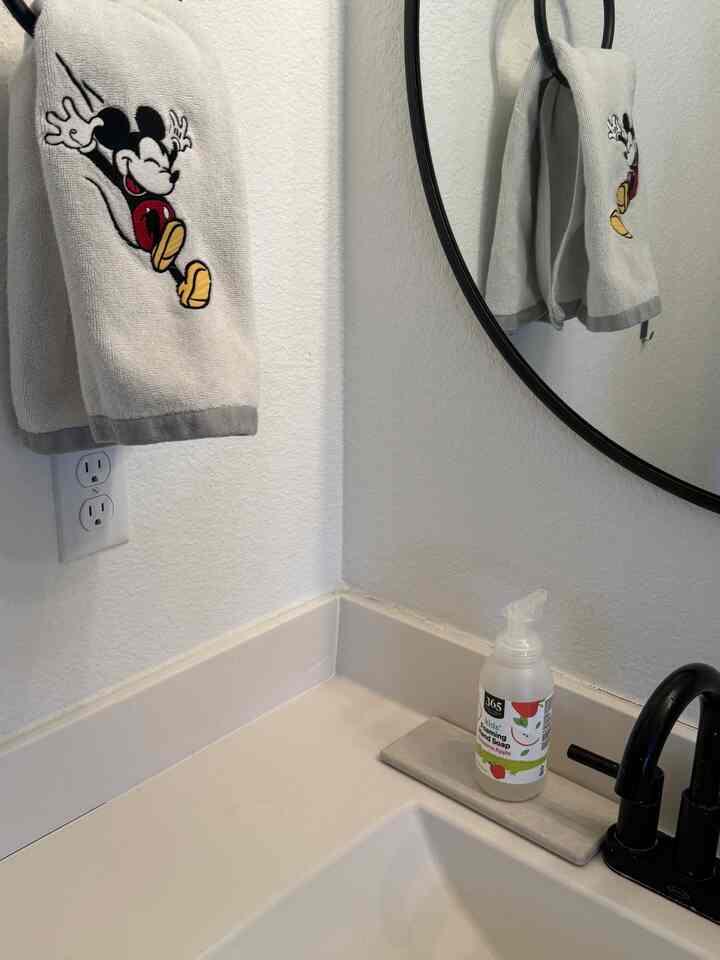 White and black toned bathroom featuring a child-friendly Mickey Mouse towel, clean and minimal atmosphere