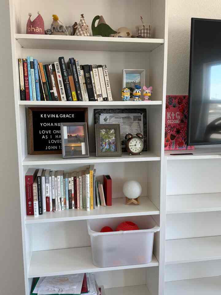 White-toned living room featuring an IKEA bookshelf with TROFAST storage box filled with books and toys, creating a cozy atmosphere