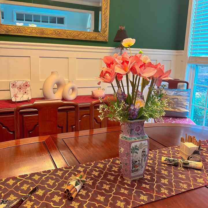 Classic dining room with brown wood furniture and green walls, featuring a central floral vase and decorative items on the table