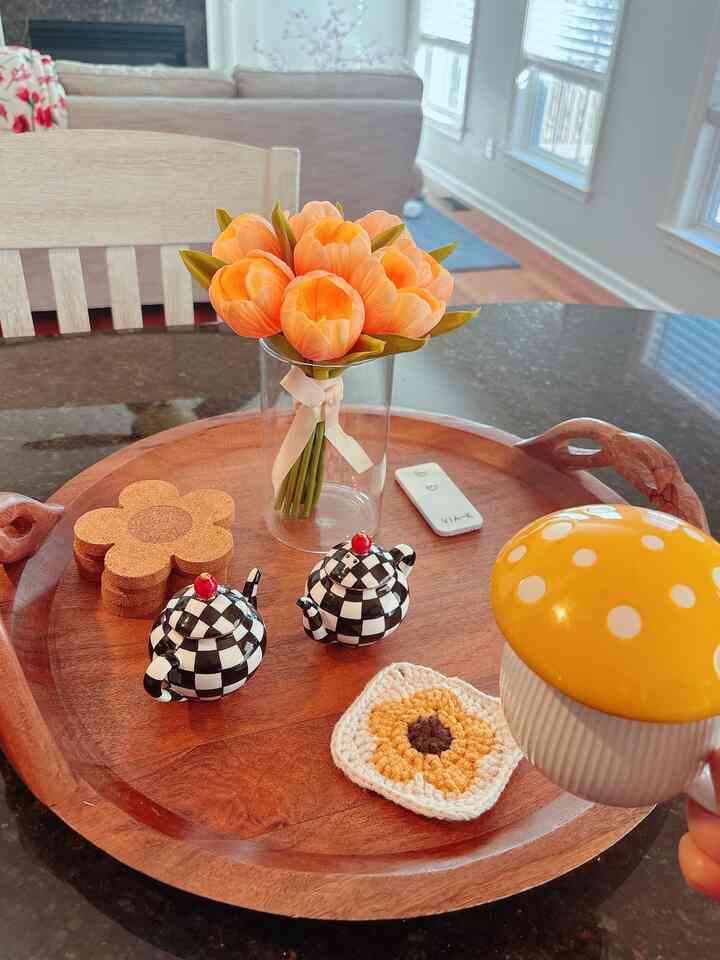 Bright yellow and brown wood-toned kitchen dining table featuring a flower vase, decorative teapot-shaped shakers, and a mushroom ceramic mug creating a cozy atmosphere