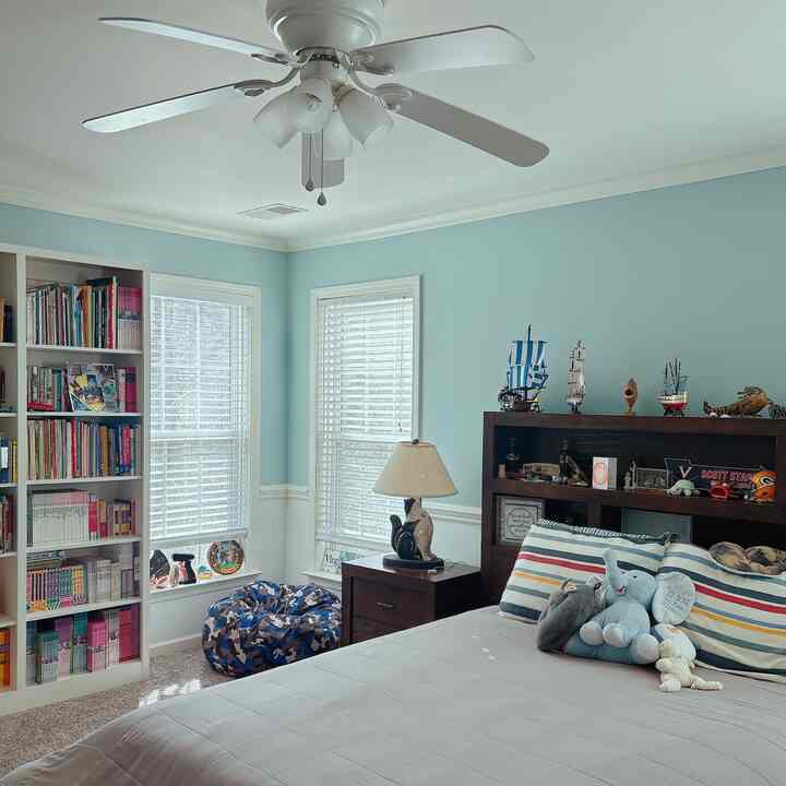 Pastel blue and white toned kids' room featuring a bookshelf and bed with cozy, tidy atmosphere