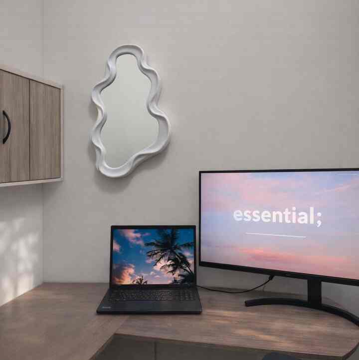Light beige toned home office space featuring a modern desk with a laptop and large monitor, creating a clean work environment