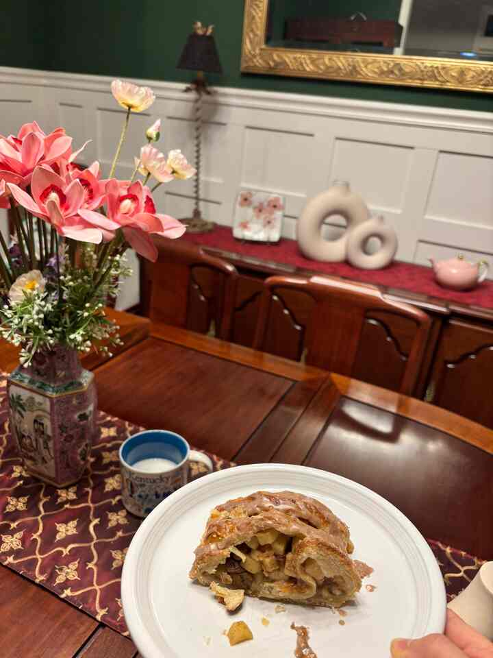Classic dining room with dark brown wooden table and chairs, featuring a pink floral vase as centerpiece