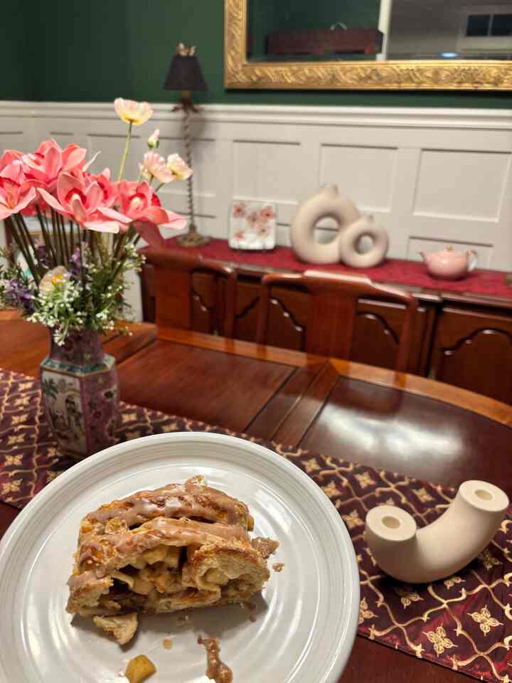 Brown-toned dining room with red table runner and vase with flowers, featuring a plate with dessert, creating a cozy atmosphere